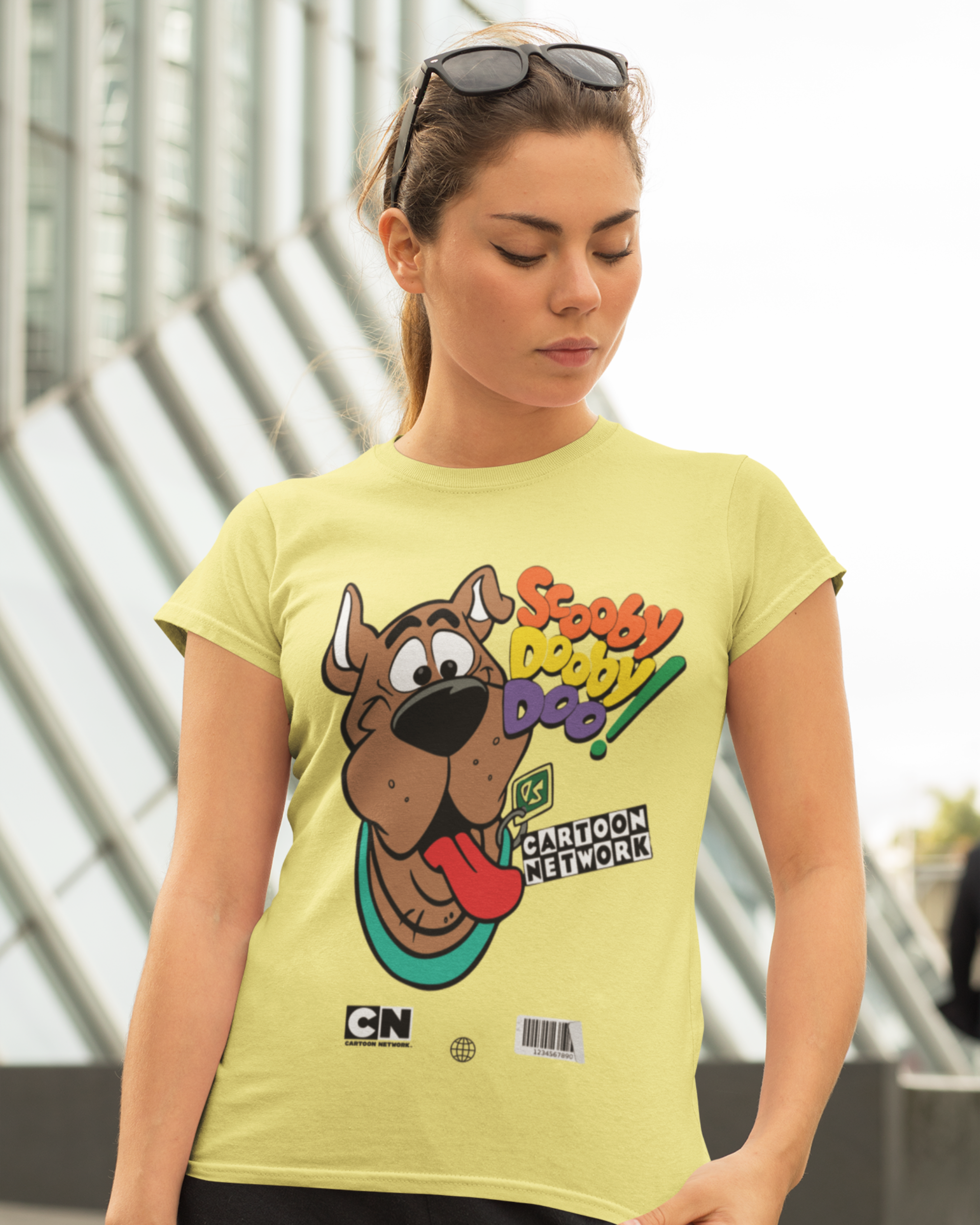 Woman wearing a yellow t-shirt with a cartoon character design, standing outdoors.