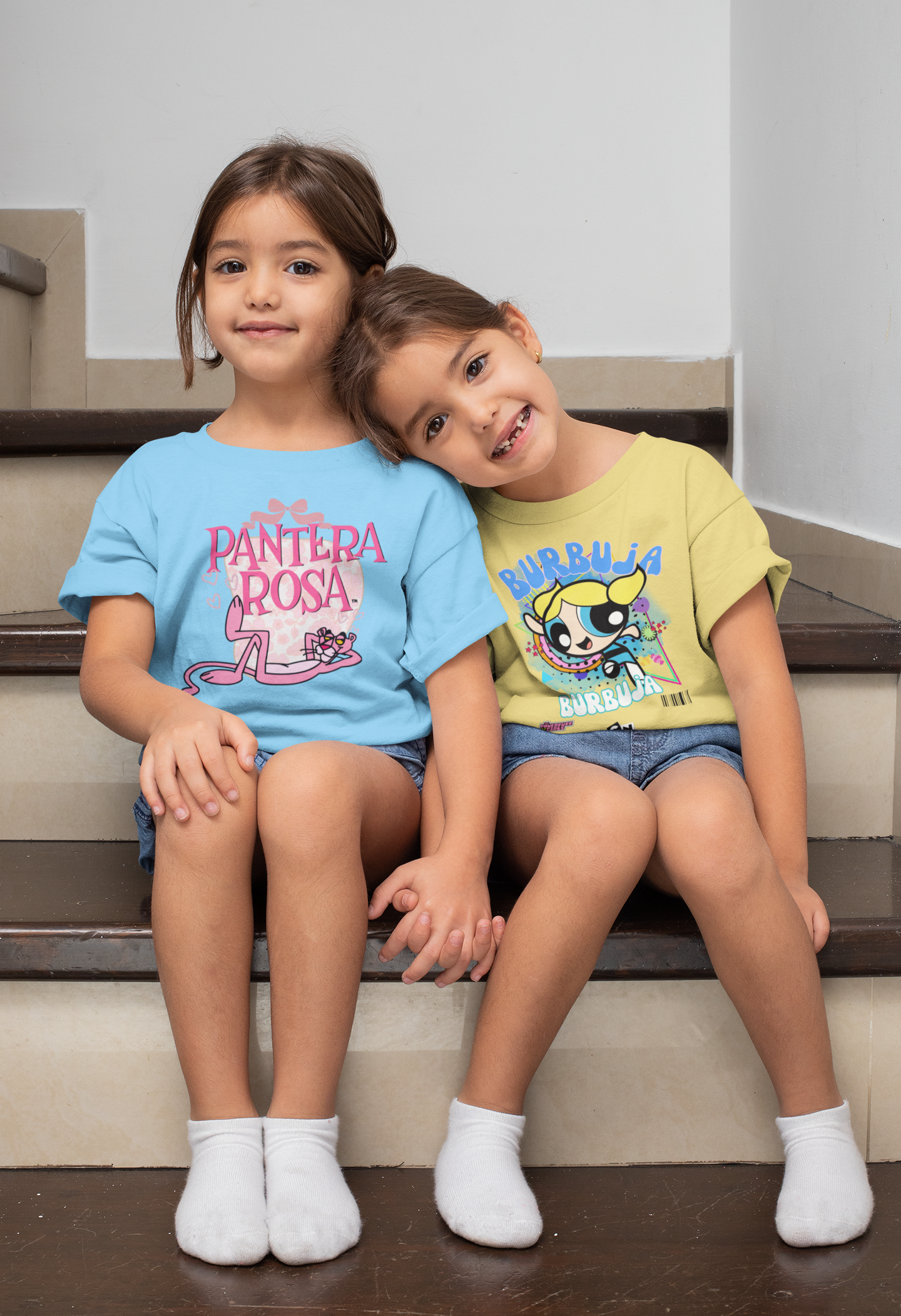 Two children sitting on stairs wearing colorful t-shirts.